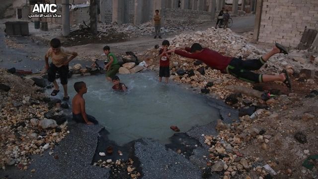 Un grupo de niños sirios usan como piscina el cráter de una bomba