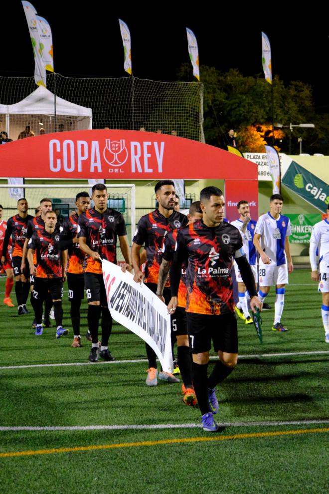 El Atlético Paso recuerdan en su partido con el RCD Español que la catástrofe volcánica continúa para miles de afectados